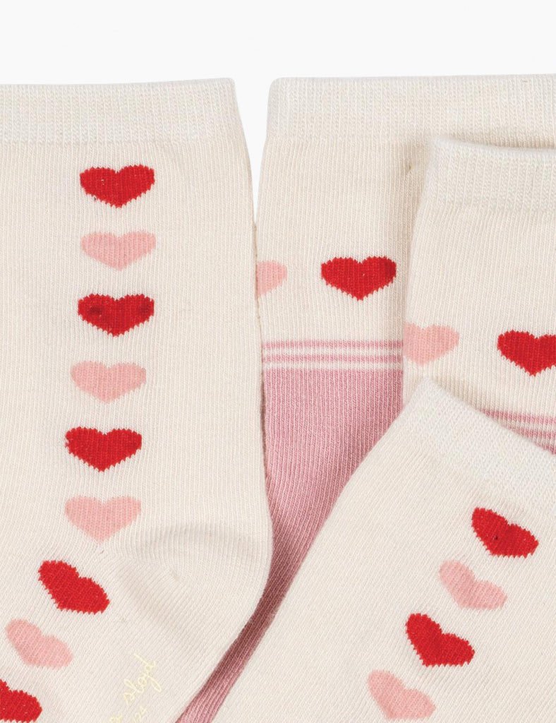 Pair of socks with red and pink heart patterns on a white background