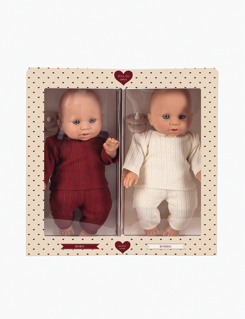 Two dolls in packaging with a heart design on a white background