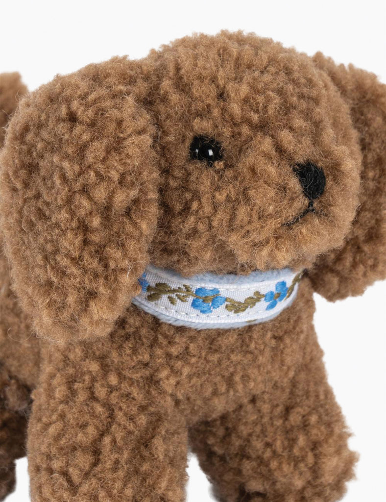 Brown teddy bear with a floral-patterned ribbon on a white background