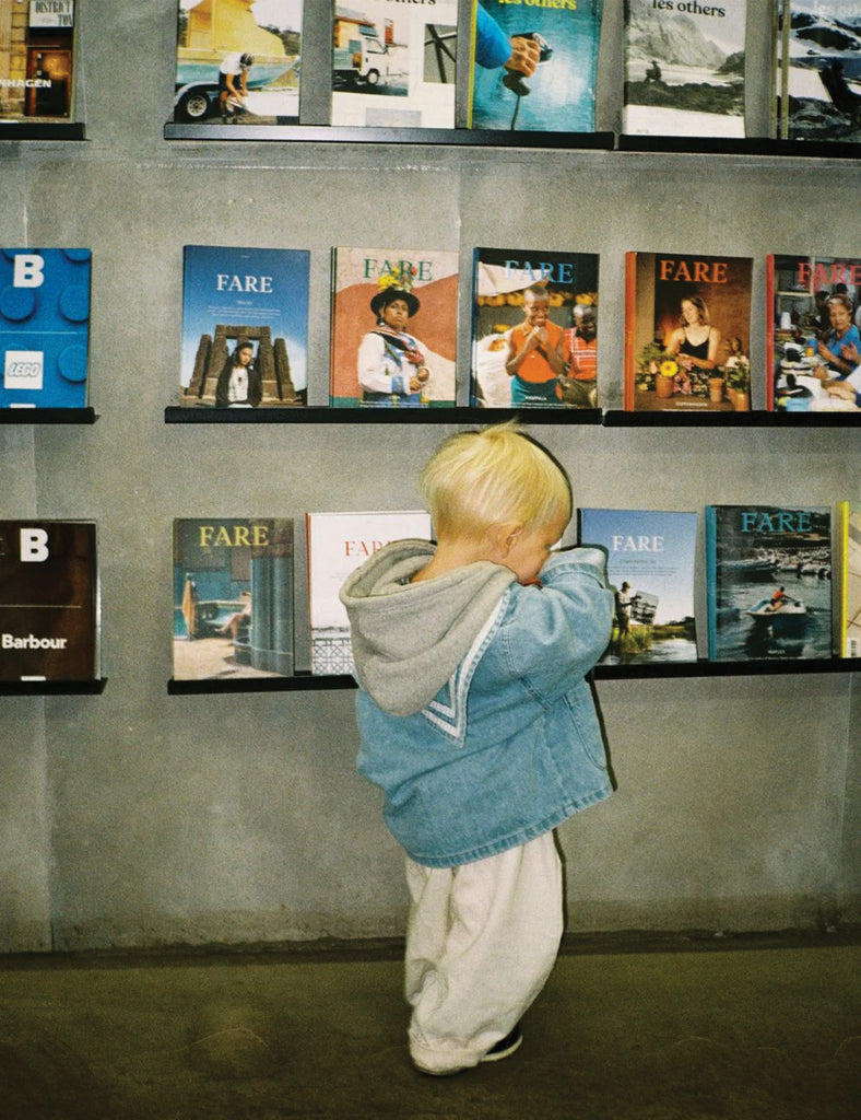 Child looking at a display of books or magazines on a shelf.