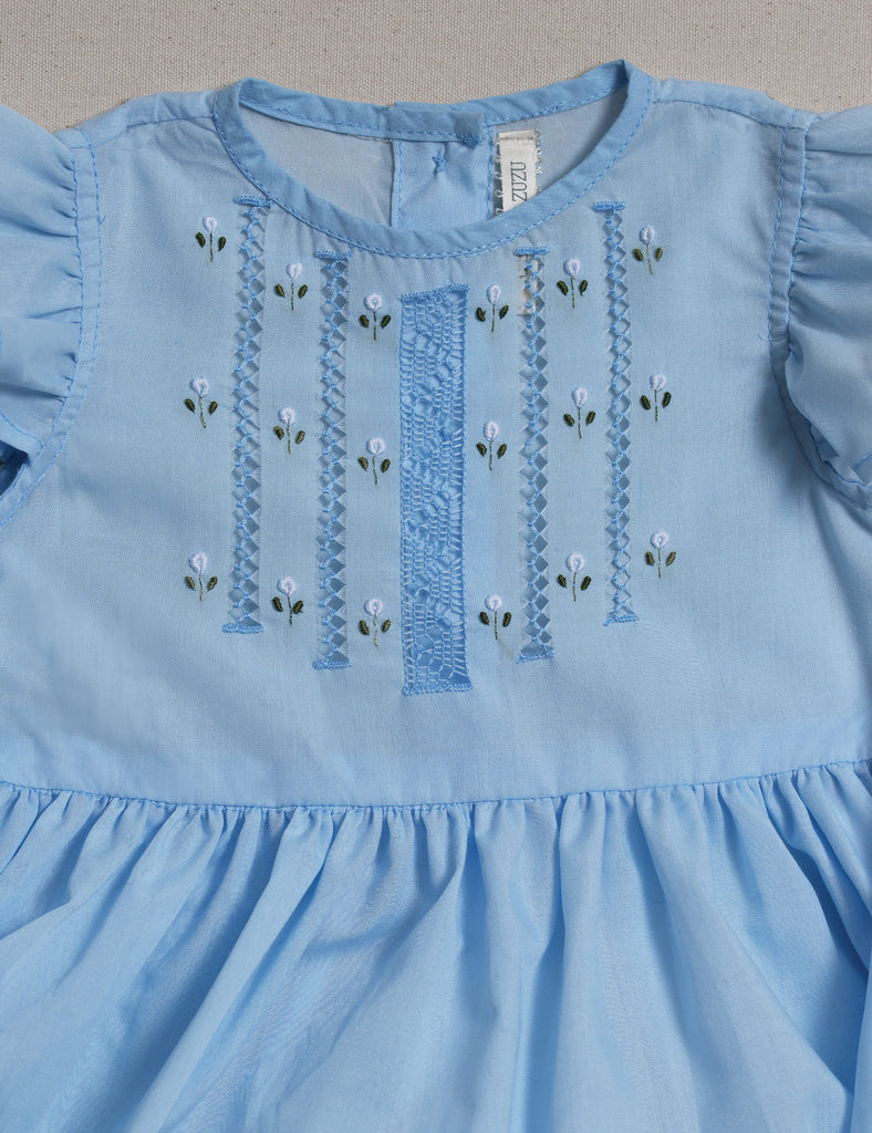 Light blue dress with floral embroidery on a neutral background