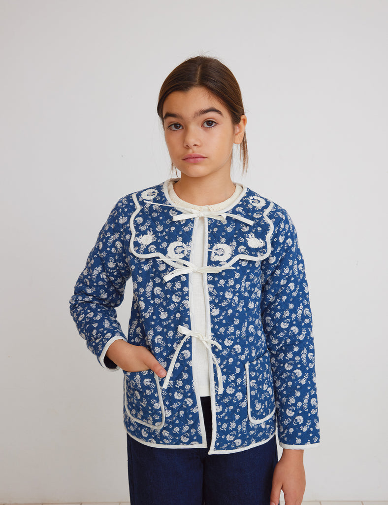 Child wearing a blue floral jacket with white accents against a plain background