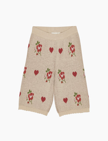 Beige pants with red heart and flower patterns on a white background