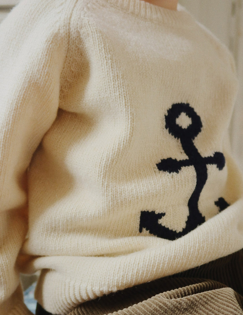Beige sweater with a black anchor design on a neutral background
