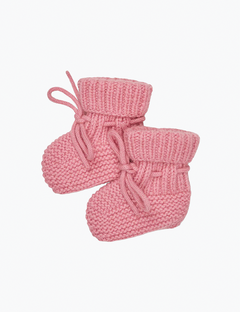Pair of pink knitted baby booties on a light pink background
