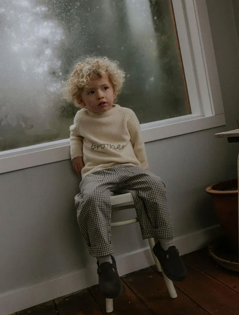 Child sitting on a stool by a window with a soft focus background