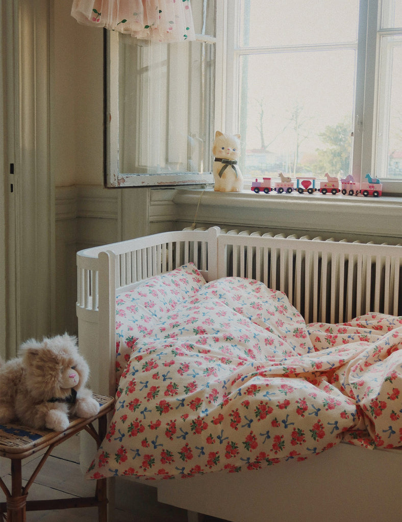 Nursery room with a crib, teddy bear, and floral bedding.