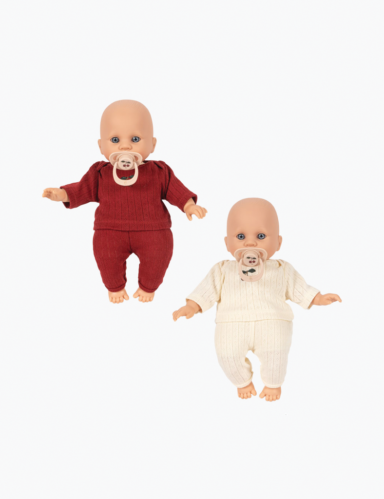 Two baby dolls, one in a red outfit and the other in a white outfit, on a white background.