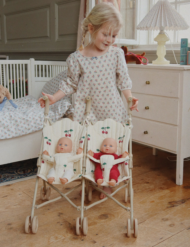 Child playing with dolls in a baby buggy in a bedroom setting