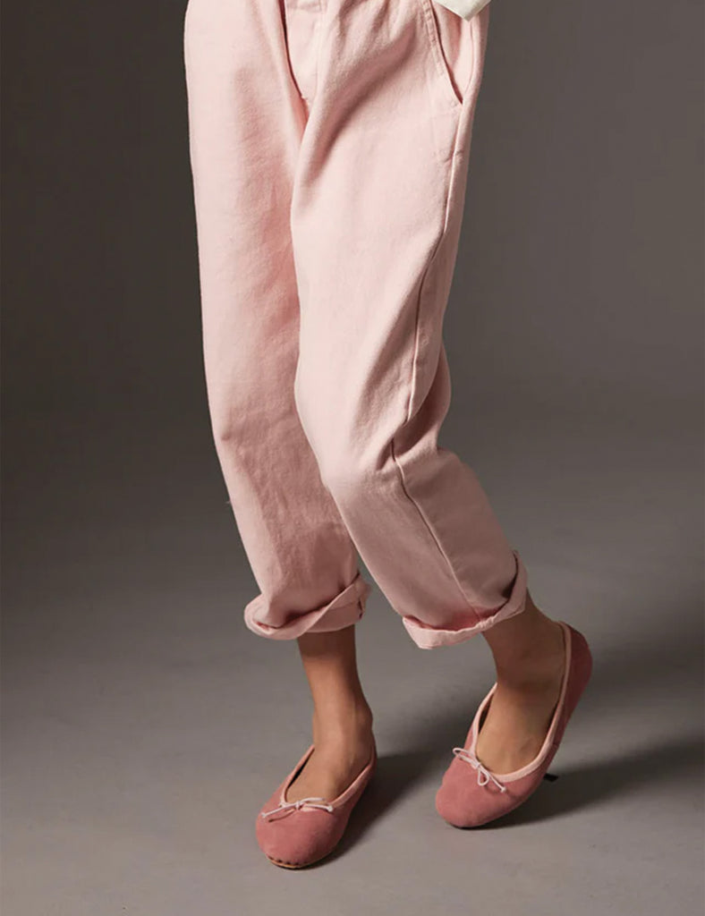 Person wearing pink pants and matching flats on a gray background
