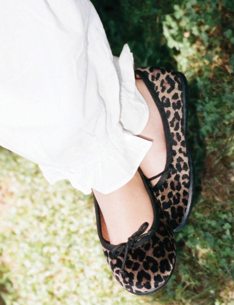 Leopard print shoes worn with white pants on a grassy background