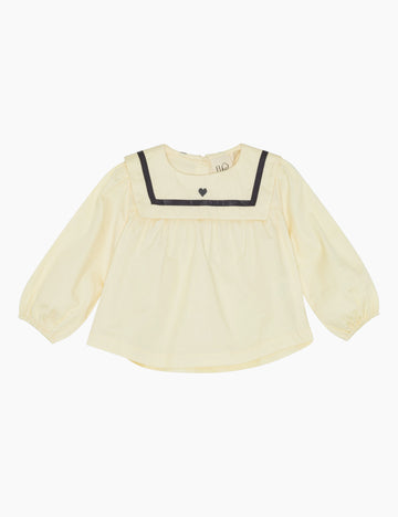 Cream blouse with navy trim on a white background