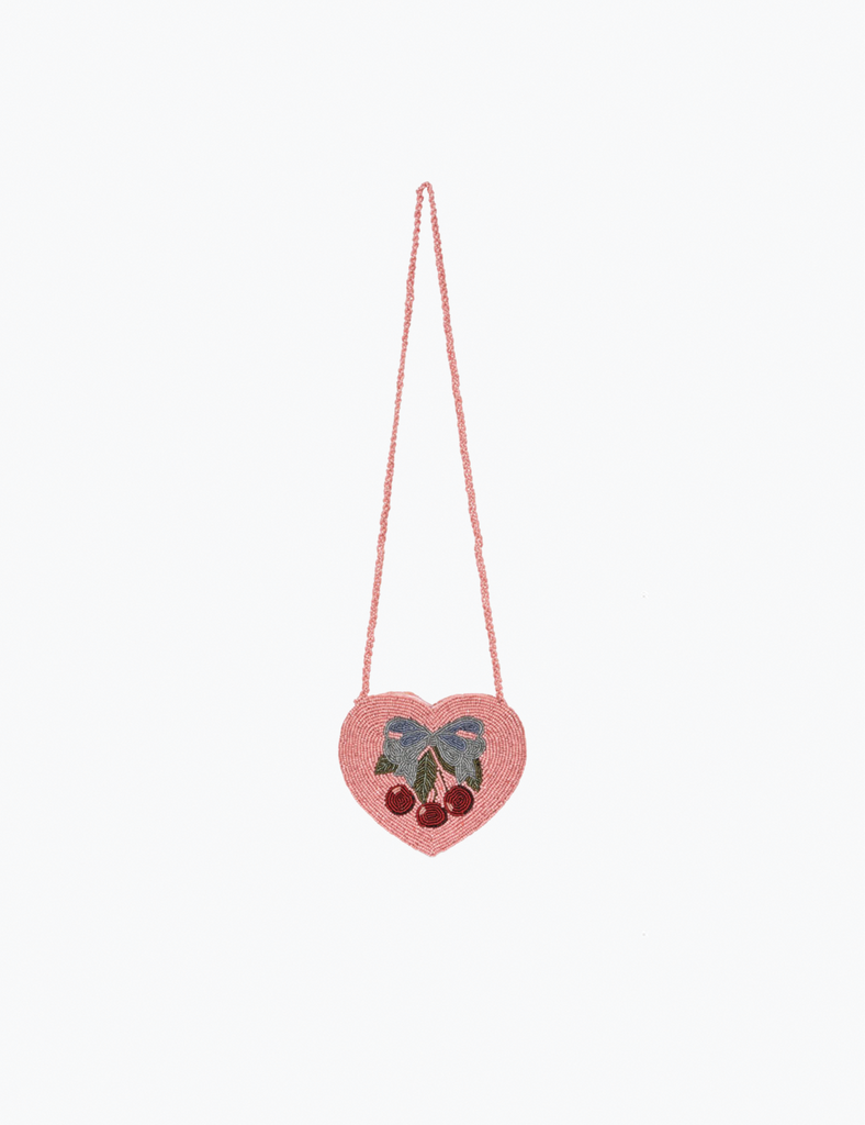Heart-shaped pink bag with a bow and berries on a light pink background