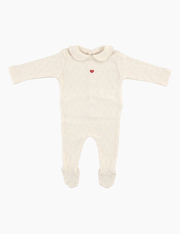 Cream-colored baby onesie with a red heart on a white background