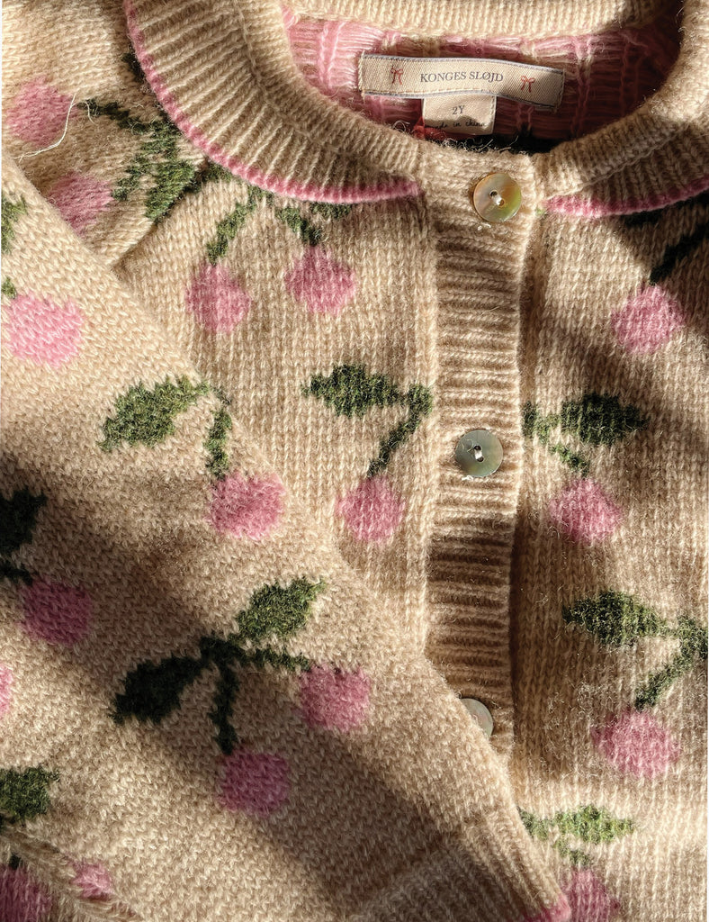 Close-up of a knitted sweater with pink floral pattern and brand label.