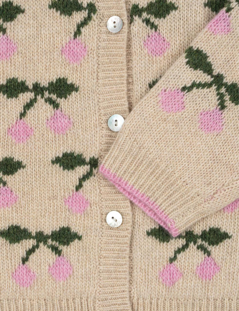 Close-up of a beige cardigan with pink floral pattern and white buttons.