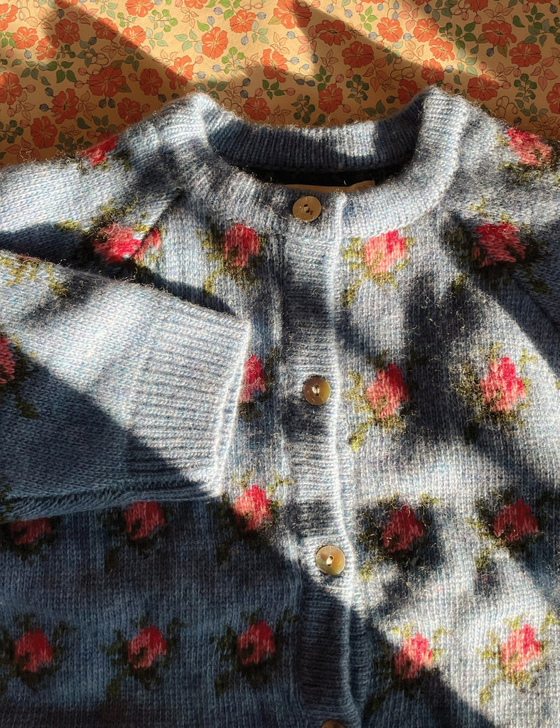 Gray knitted sweater with floral patterns on a floral fabric background