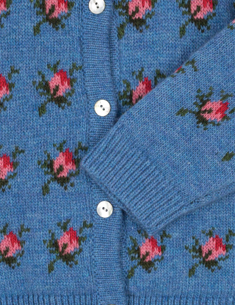 Close-up of a blue cardigan with floral patterns and buttons.