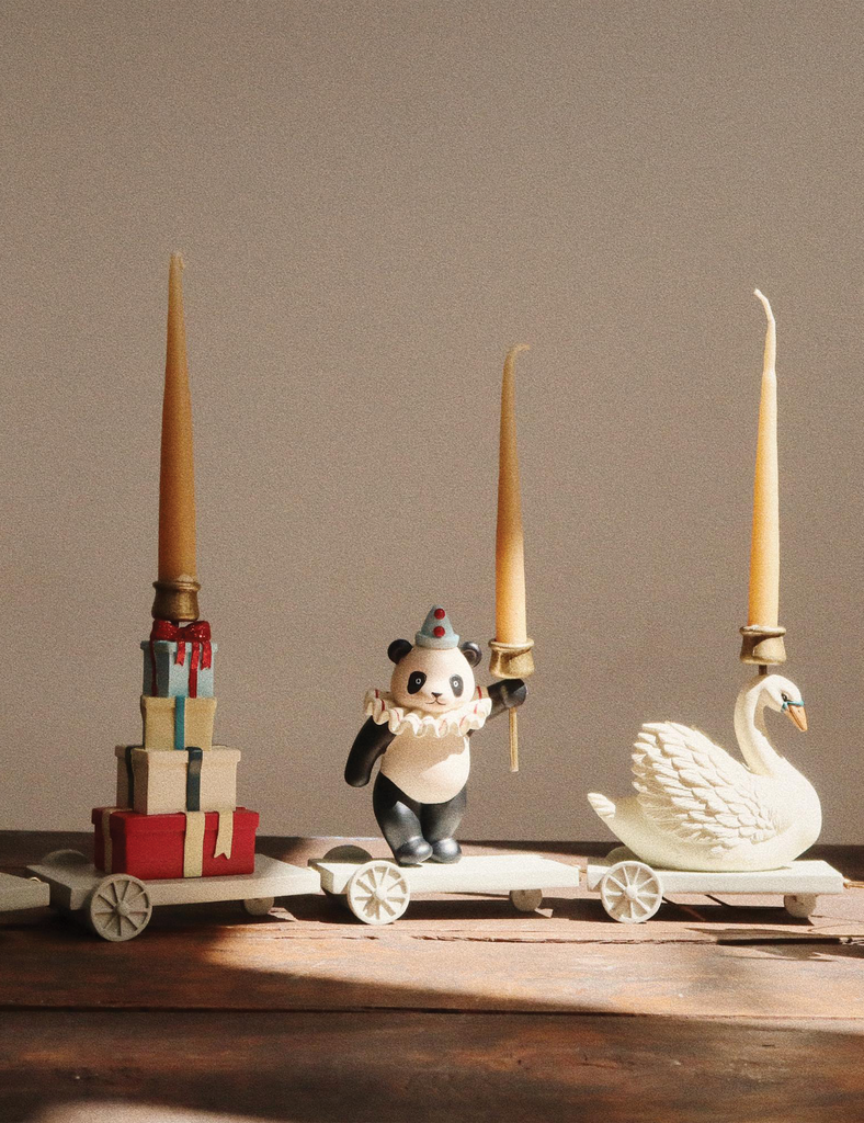 Decorative items including a panda figurine, swan, and candles on a wooden surface with a neutral background.