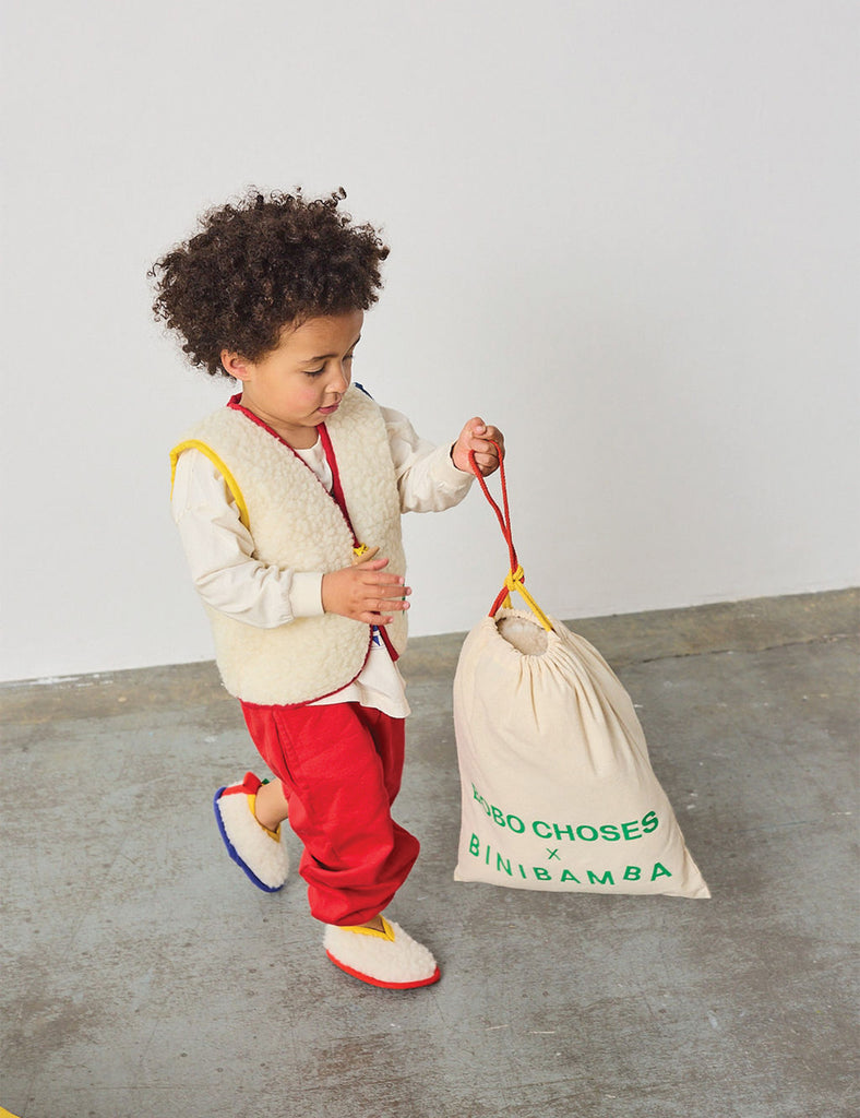 Child holding a drawstring bag with branding on a plain background