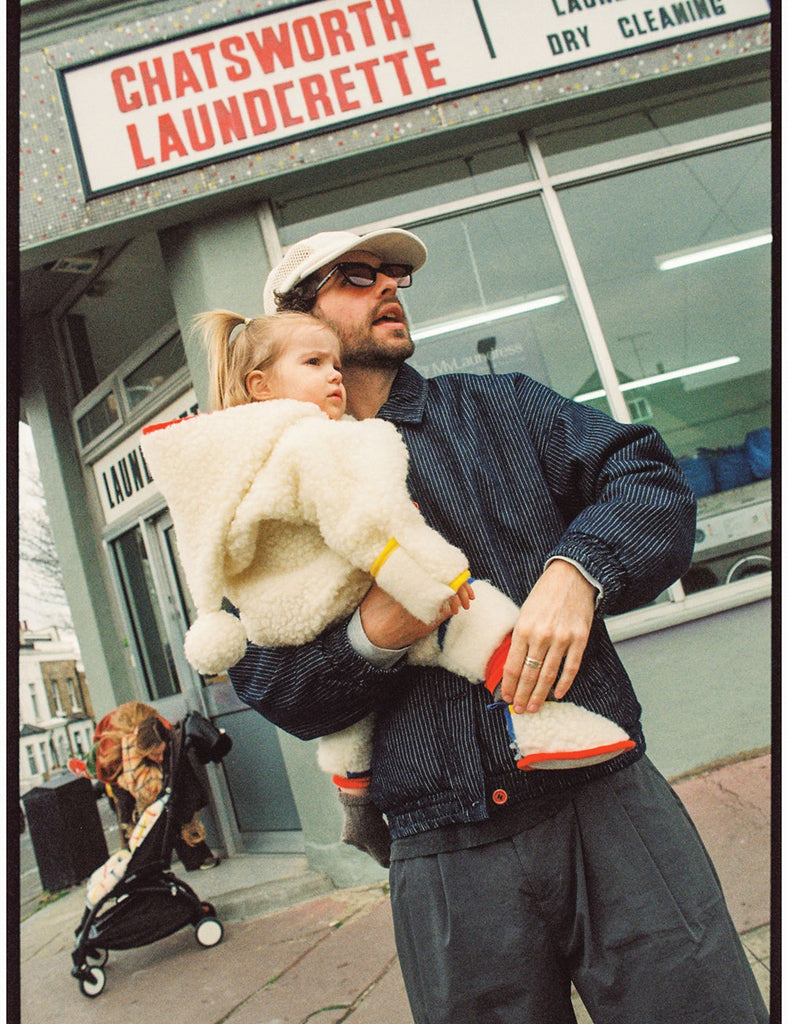 Man holding a child in front of Chatsworth Laundrette