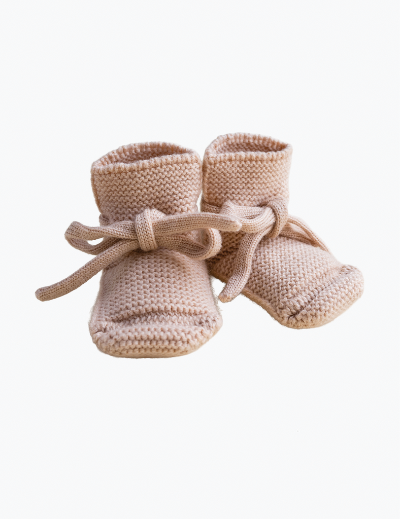 Pair of beige knitted baby booties on a white background
