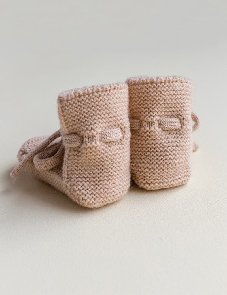 Pair of pink knitted baby booties on a light background