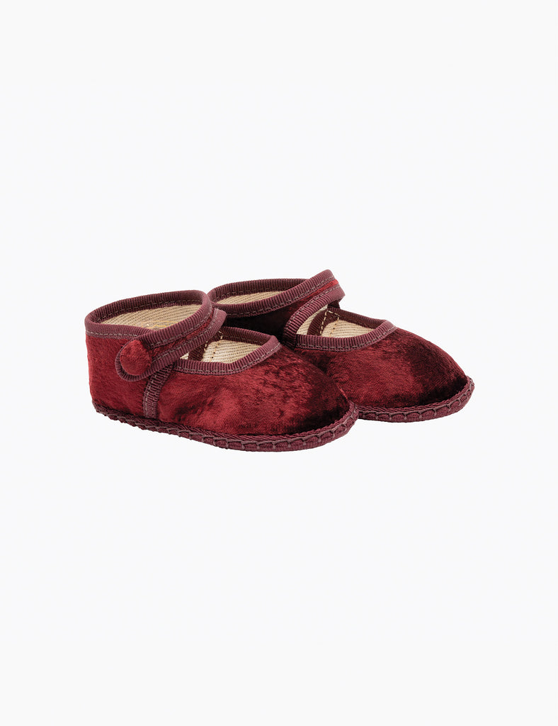 Pair of red velvet baby shoes on a white background