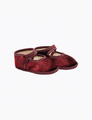 Pair of red velvet baby shoes on a white background