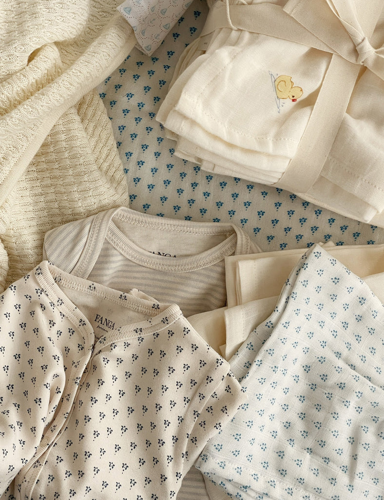 Collection of baby clothes with floral patterns on a textured fabric background