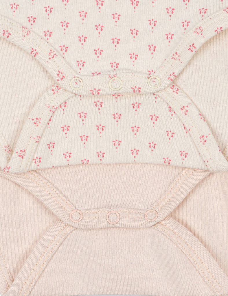 Close-up of a baby garment with pink floral pattern on a light pink background
