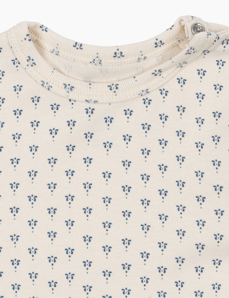 Close-up of a baby outfit with a subtle blue floral pattern on a white background