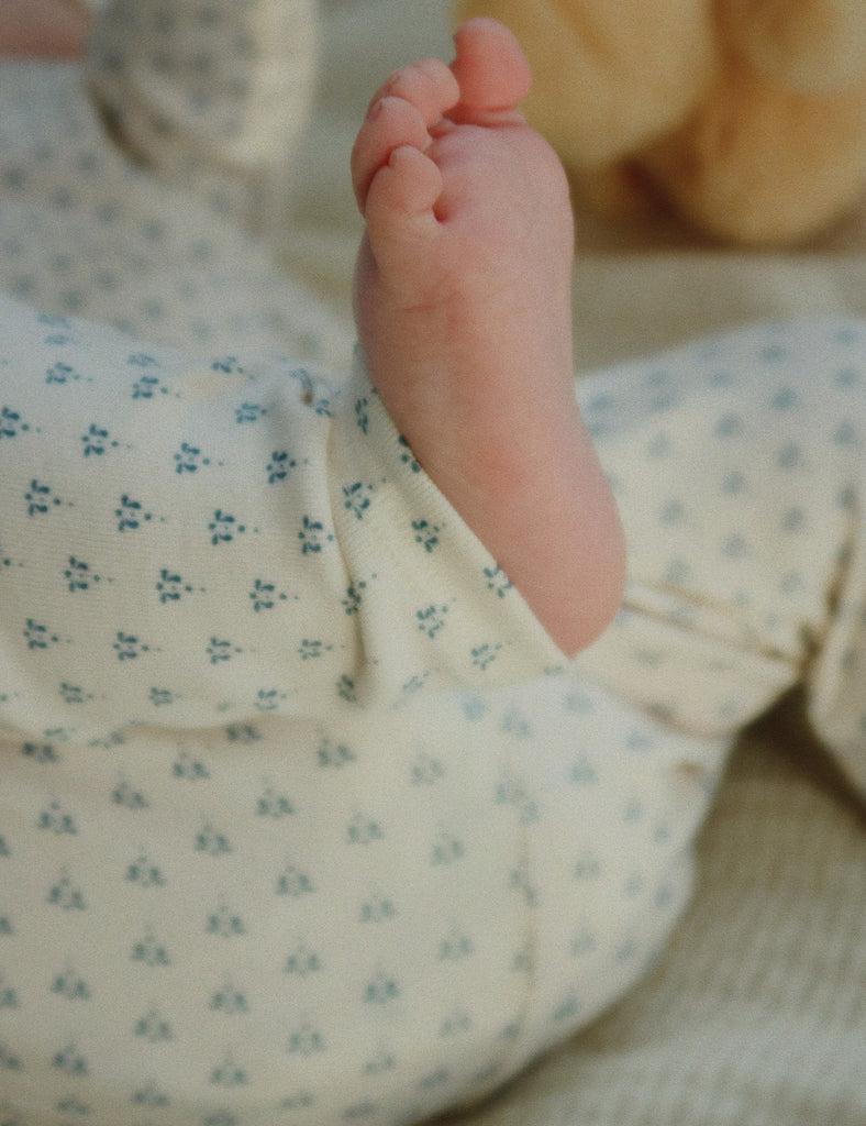 Baby foot peeking out from a floral outfit with a soft focus background