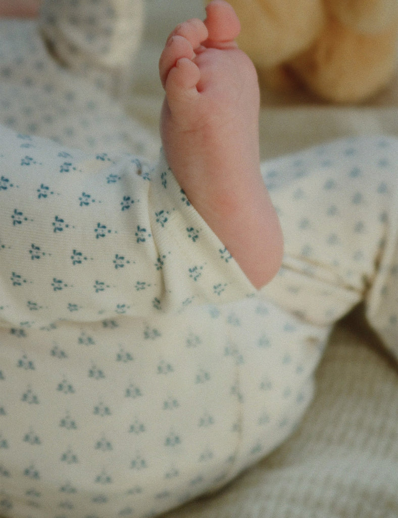 Baby's foot peeking out from a floral outfit with a soft focus background