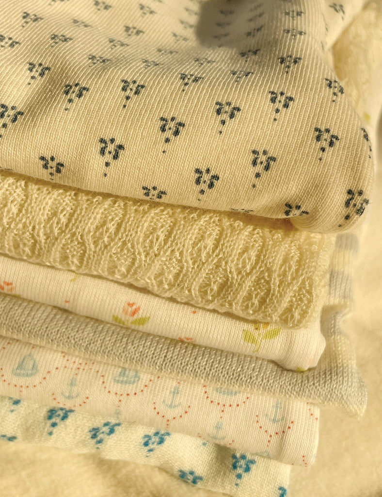 Stack of fabric swatches with various patterns on a neutral background