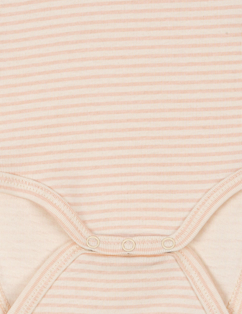 Close-up of a ribbed fabric with buttons on a light pink background