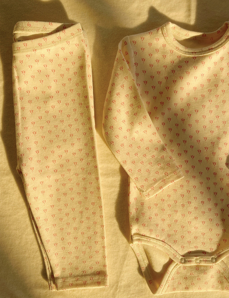 Pink polka dot long-sleeve bodysuit on a white background