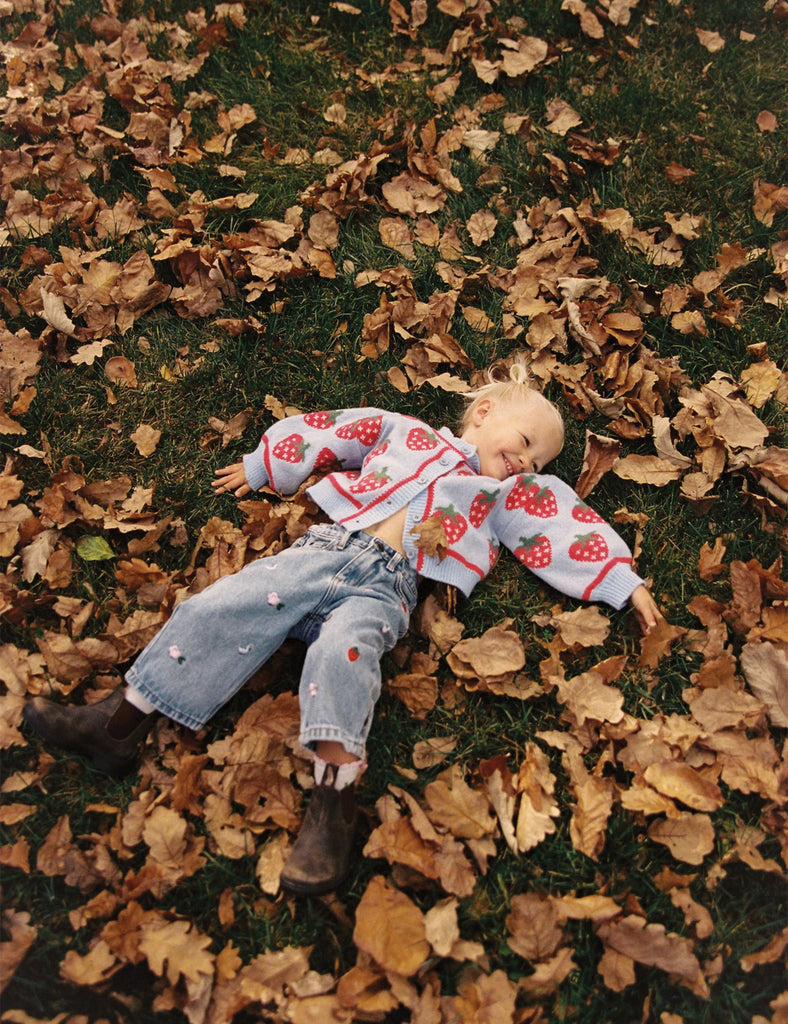 Little girl lying on a bed of autumn leaves