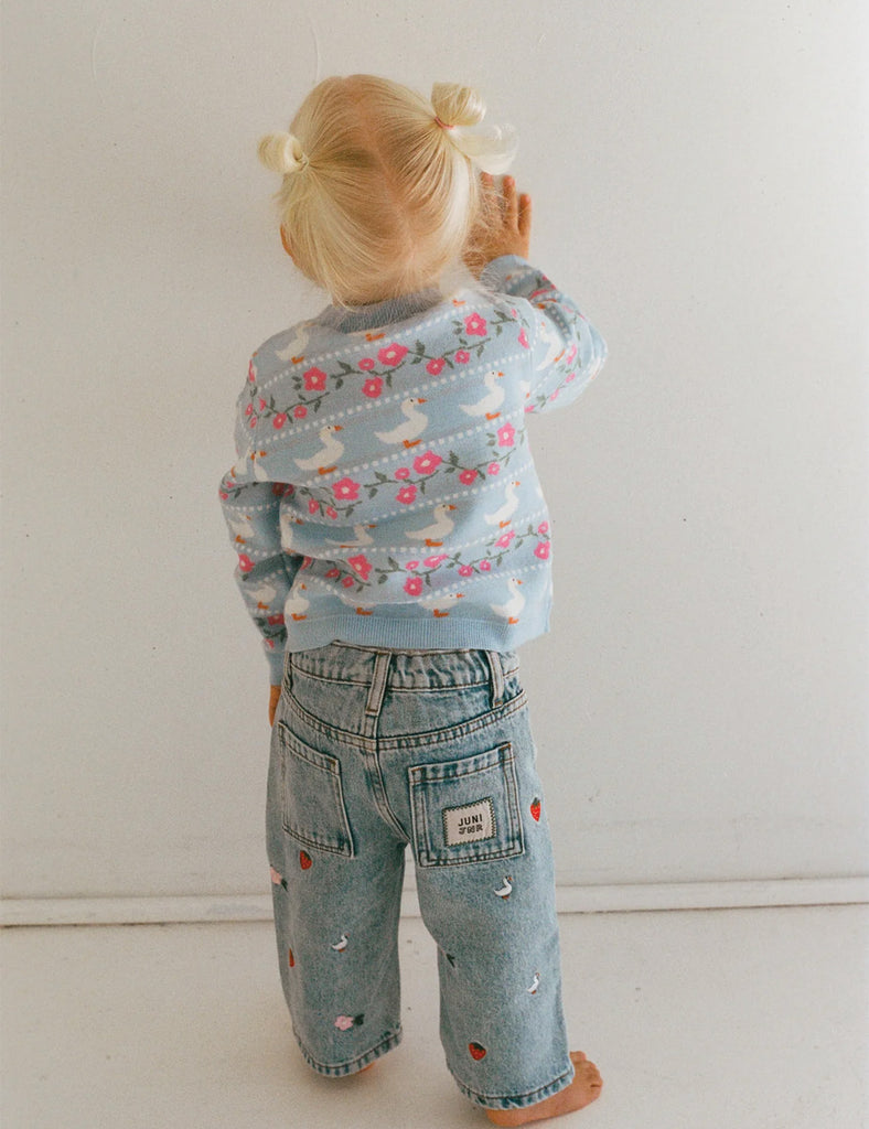 Child wearing a floral jacket and jeans on a plain background