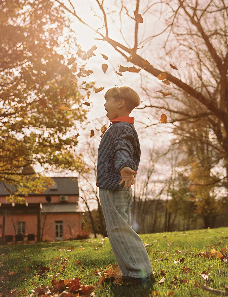 Child playing with leaves in a park during autumn