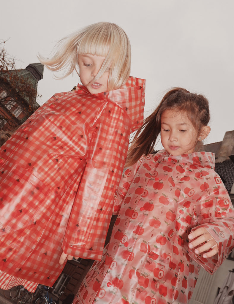 Two children wearing red raincoats with a checkered pattern.