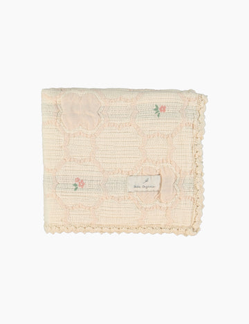 Textured blanket with floral embroidery on a white background