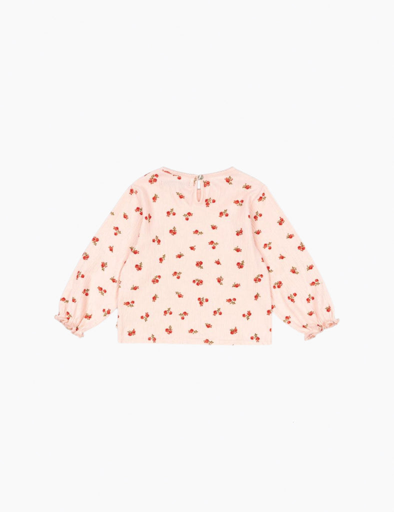 Pink long-sleeve top with red floral pattern on a white background