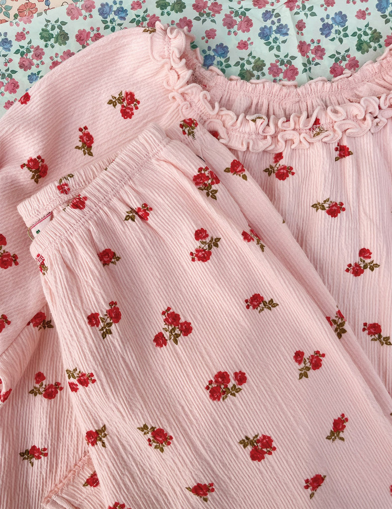 Close-up of a pink fabric with red floral patterns against a floral background