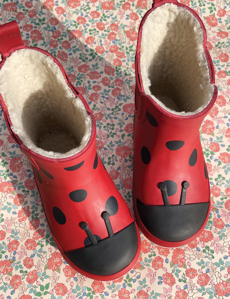 Image of child's rainboots with an allover ladybug print on a white background.