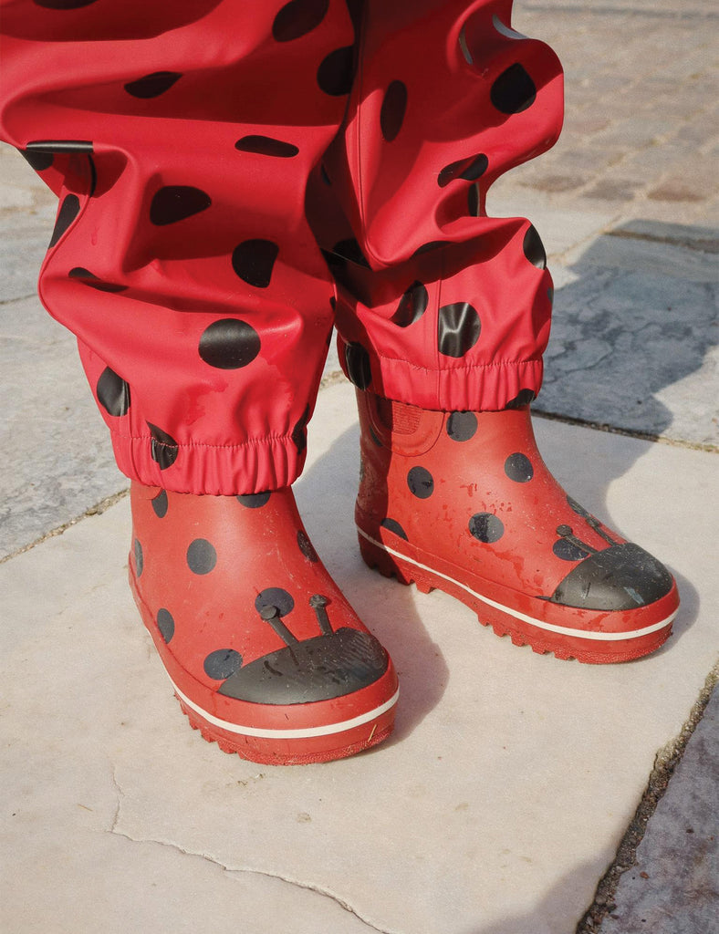 Image of child's rainboots with an allover ladybug print on a white background.