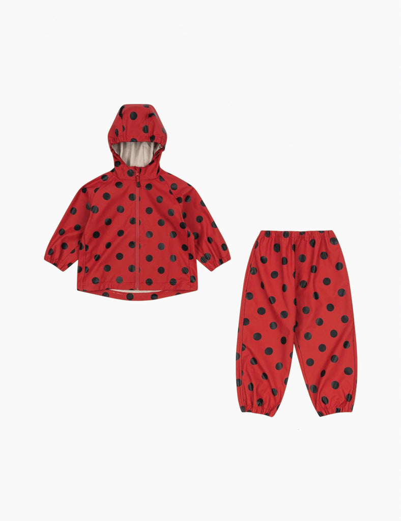 Image of a child's matching hooded rain jacket and pant set featuring a red ground with allover ladybug black dot print.