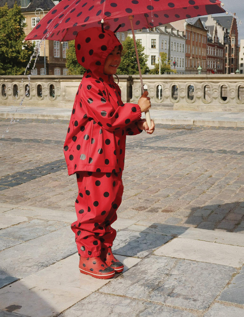 Image of a child wearing a matching hooded jacket and pant rain set. 