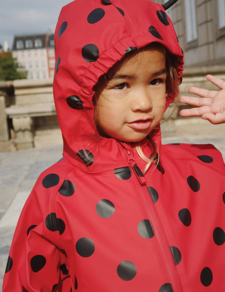 Image of a child wearing a matching hooded jacket and pant rain set. 