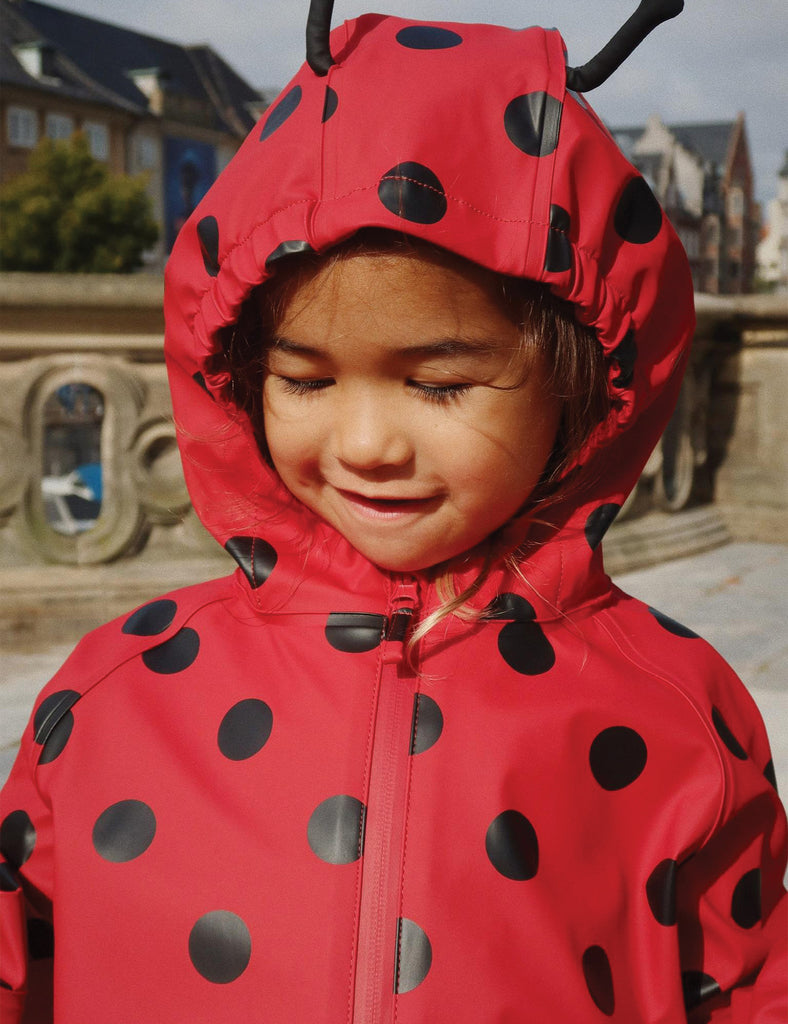 Image of a child wearing a matching hooded jacket and pant rain set. 